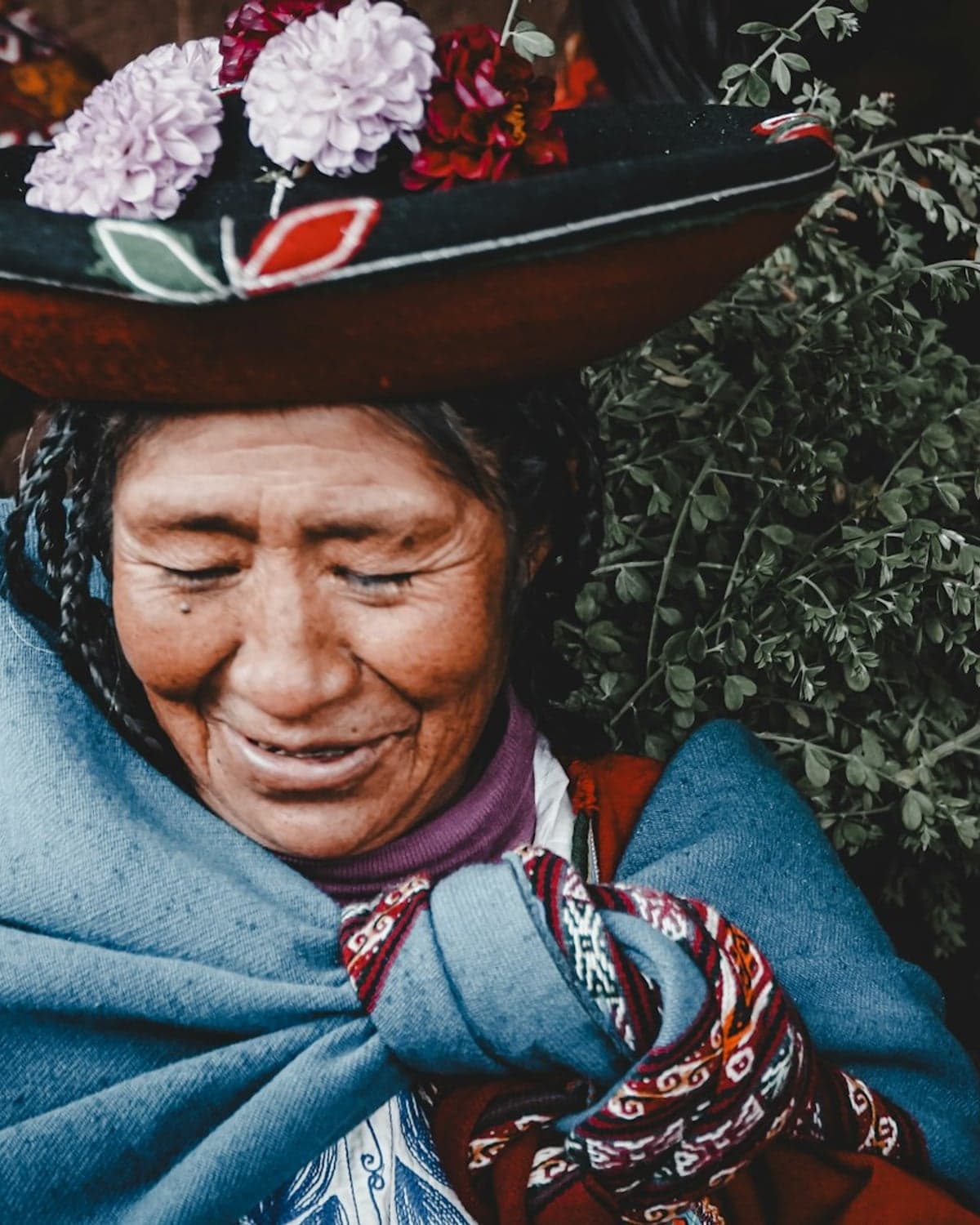 Anciana andina con sombrero adornado de flores, sonrisa serena, manta tradicional